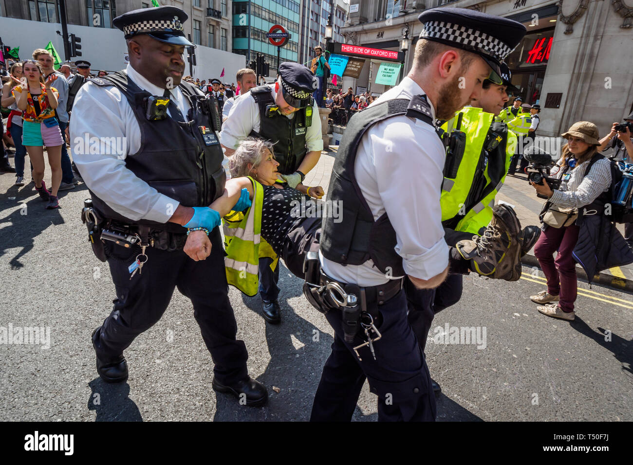 London, Großbritannien. 19. April 2019. Polizei weg eine Person, die bei der Löschung Rebellion Meer von Protest verhaftet wurde, nachdem die Polizei die Yacht umgeben und einen Ring von Offizieren, um Oxford Circus. Die Polizei versucht, die Demonstranten zu überzeugen, indem sie drohen mit Verhaftung zu verlassen. Später gab es eine Reihe von Verhaftungen von Demonstranten, die sich weigerten, zu verlassen. Ein paar versucht, die große Masse der Yacht zu schützen, zu erhalten, aber XR Veranstalter überzeugte sie nicht die Polizei Aktion physisch zu widersetzen. Peter Marshall / alamy Leben Nachrichten Stockfoto