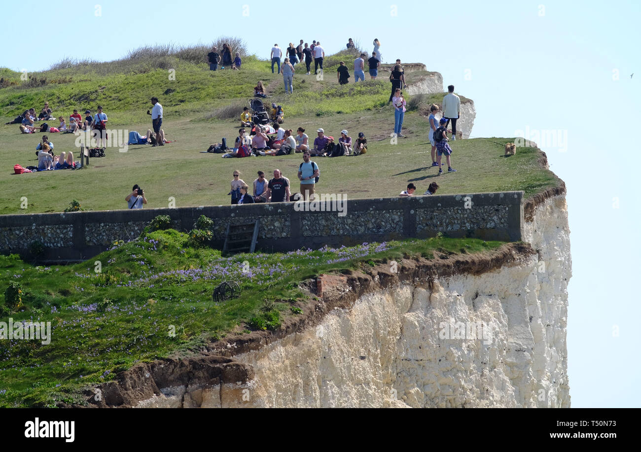 Birling Gap, East Sussex, UK. 20. April 2019. Die ungewöhnlich warmen Wetter hat gesehen, tausende von Touristen strömen zu den ikonischen Sieben Schwestern Kreidefelsen in der Nähe von Eastbourne, East Sussex, von denen viele gefährliche selfieis auf der unstable Klippe. Ein Mann wurde gesehen baumelt ein kleines Kind in seine Arme, als er über die schiere Drop spähte. Die Klippen sind bis zu 400 Fuß hoch und sind eine bekannte Selbstmord. © Peter Cripps/Alamy leben Nachrichten Stockfoto