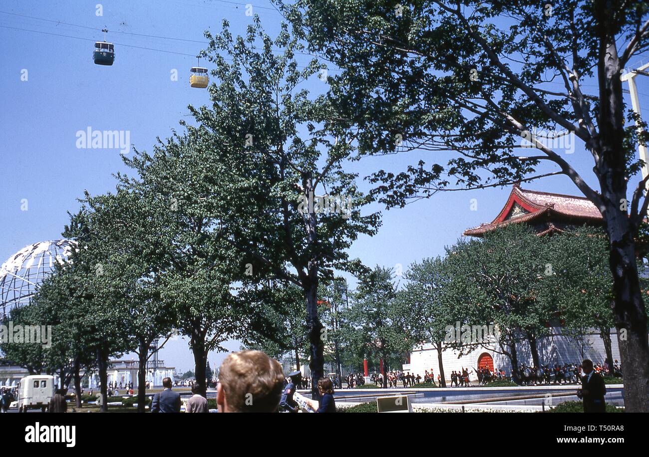 Ein paar Schweizer Himmel fahren Gondeln, an einem sonnigen Tag, einem überfüllten Baum pass gesäumten Pfad in der Nähe der reflektierenden Pool, China Pavillon und Unisphere, in New York World's Fair, Flushing Meadows Park, Queens, New York, Juni 1964. () Stockfoto