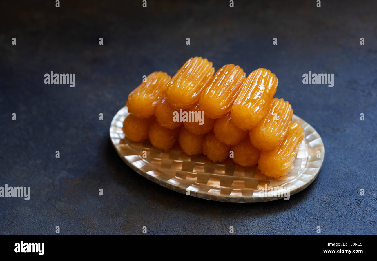 Traditionelle Dessert tulumba genannt. Türkische Küche. Balkan Küche. Levantinischen Küche. Auf einem blauen Hintergrund, serviert auf einem Vintage orientalische Platte Stockfoto