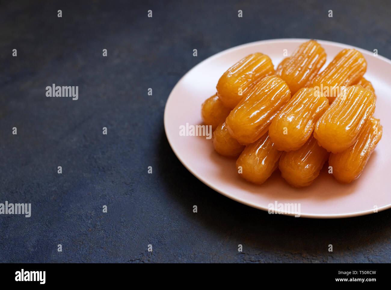 Traditionelle Dessert tulumba genannt. Türkische Küche. Balkan Küche. Levantinischen Küche. Auf einem blauen Hintergrund, serviert auf einem rosa Platte Stockfoto