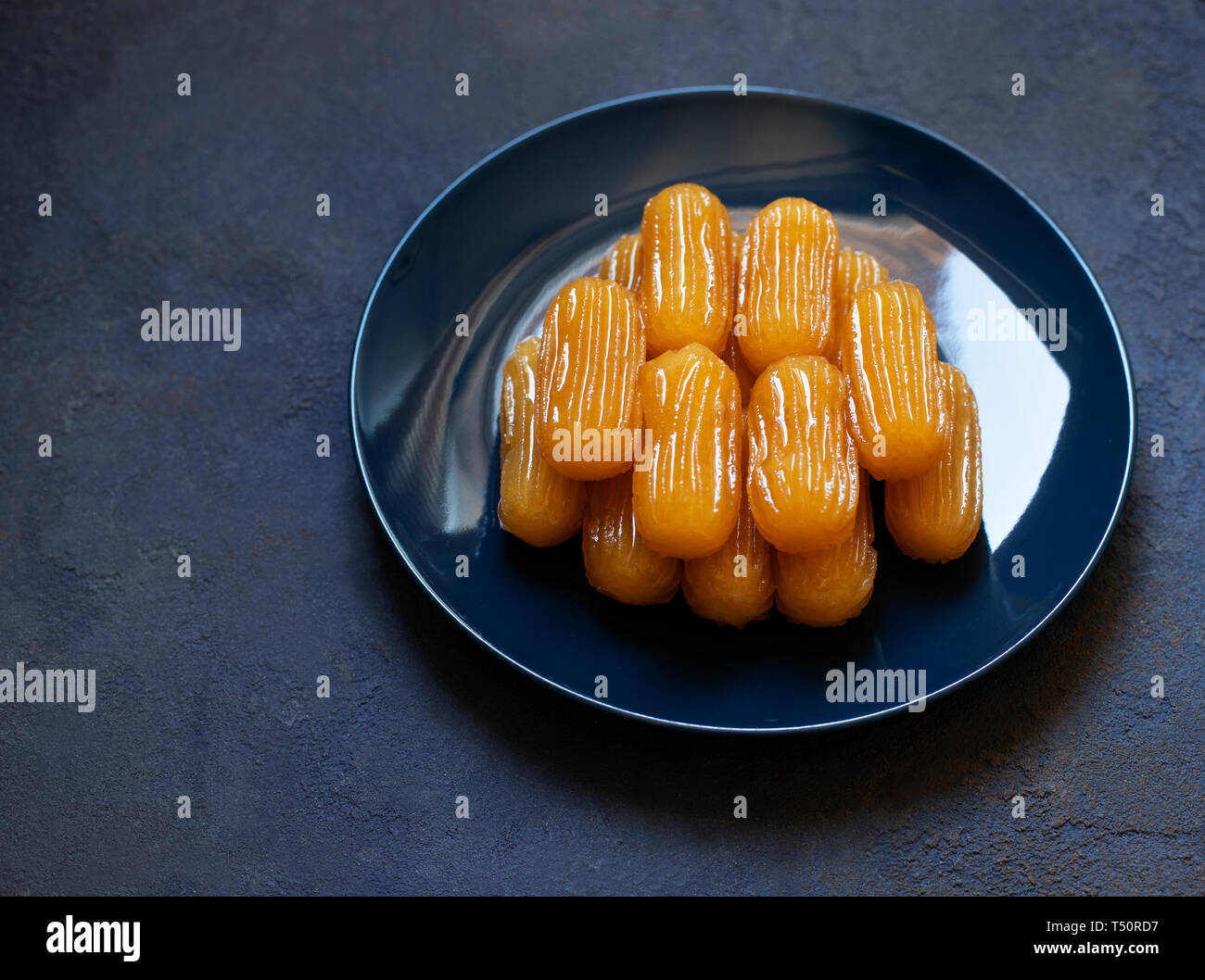 Traditionelle Dessert tulumba genannt. Türkische Küche. Balkan Küche. Levantinischen Küche. Auf einem blauen Hintergrund, serviert auf einem blauen Platte Stockfoto