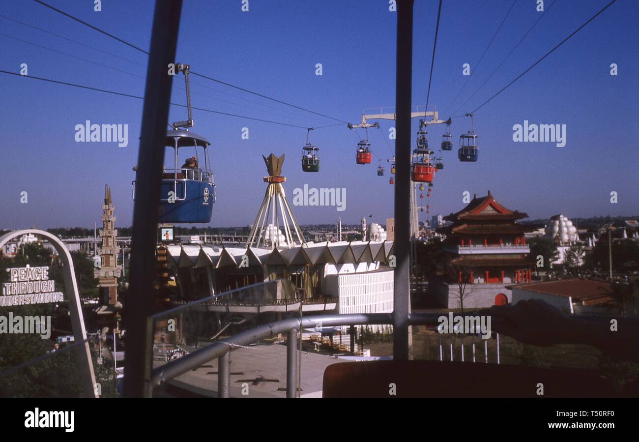 Weite Einstellung, an einem sonnigen Tag, der Schweizer Himmel fahren Gondeln über der Indonesien Pavillon und andere Exponate auf der 1964 in New York World's Fair reisen, Flushing Meadows Park, Queens, New York, Mai, 1964. () Stockfoto