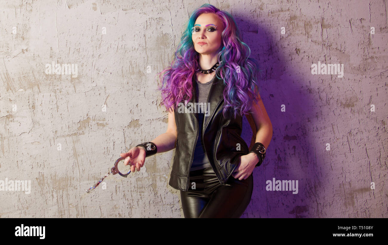 Gewagte rebel Rocker, ein Porträt auf einem Hintergrund von grauen grunge Wand. Junge stilvolle Frau in Schwarz Leder Kleidung mit gefärbten Haaren. Helle Haarfarbe. Stockfoto