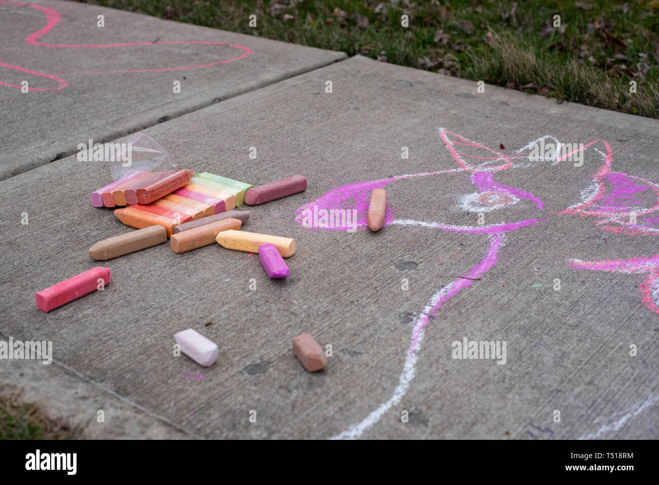 Ein kleines Mädchen, zieht mit sidewalk Chalk an einem sonnigen Frühlingstag. Stockfoto