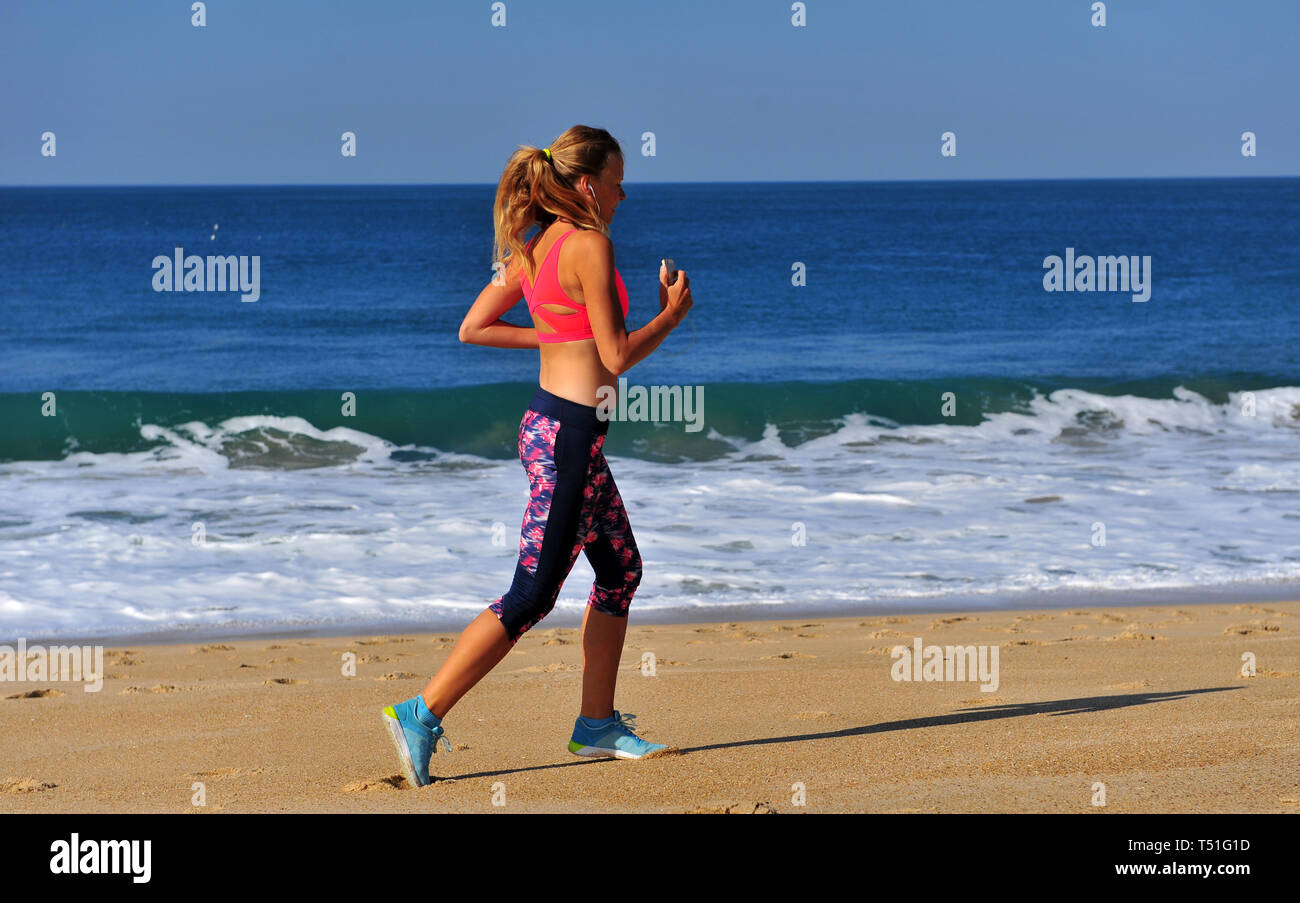 Genießen Sie die Küsten-Vibes: Jog on the Beach einer jungen Frau, die Sonne, Sand und die Ruhe der Natur genießen Stockfoto