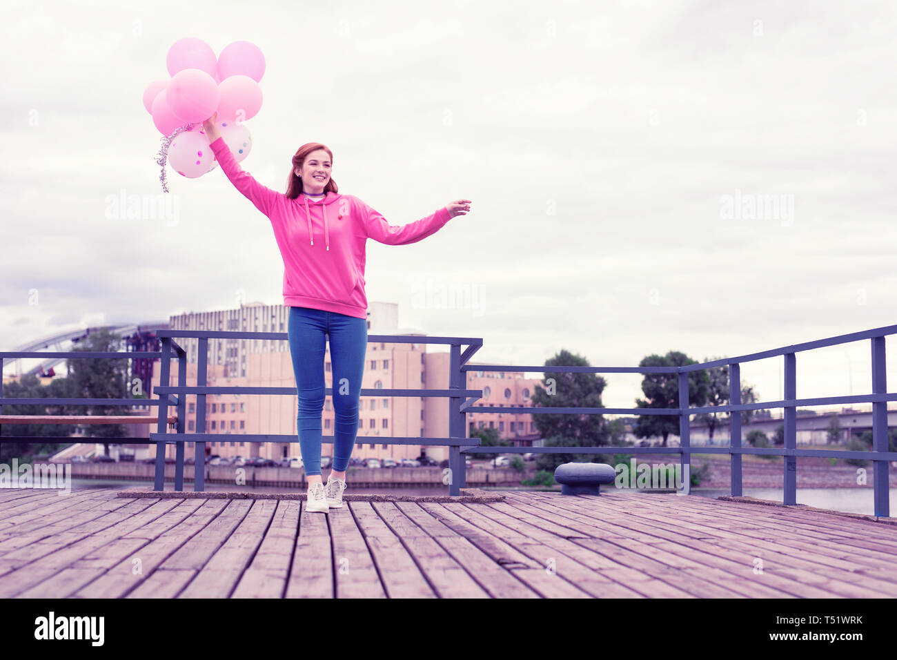 Übertragen von Ingwer Frau gehen auf hölzernen Pier mit Ballons Stockfoto