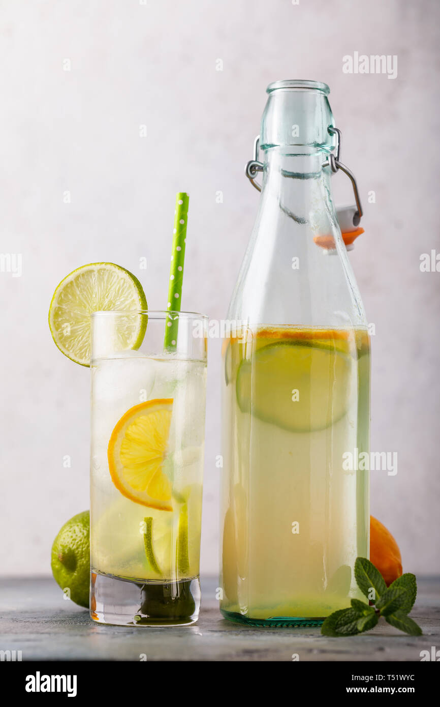 Tonic trinken mit Zitrone und Limette in ein durchsichtiges Glas mit einer offenen Flasche auf den Tisch, Nahaufnahme Stockfoto