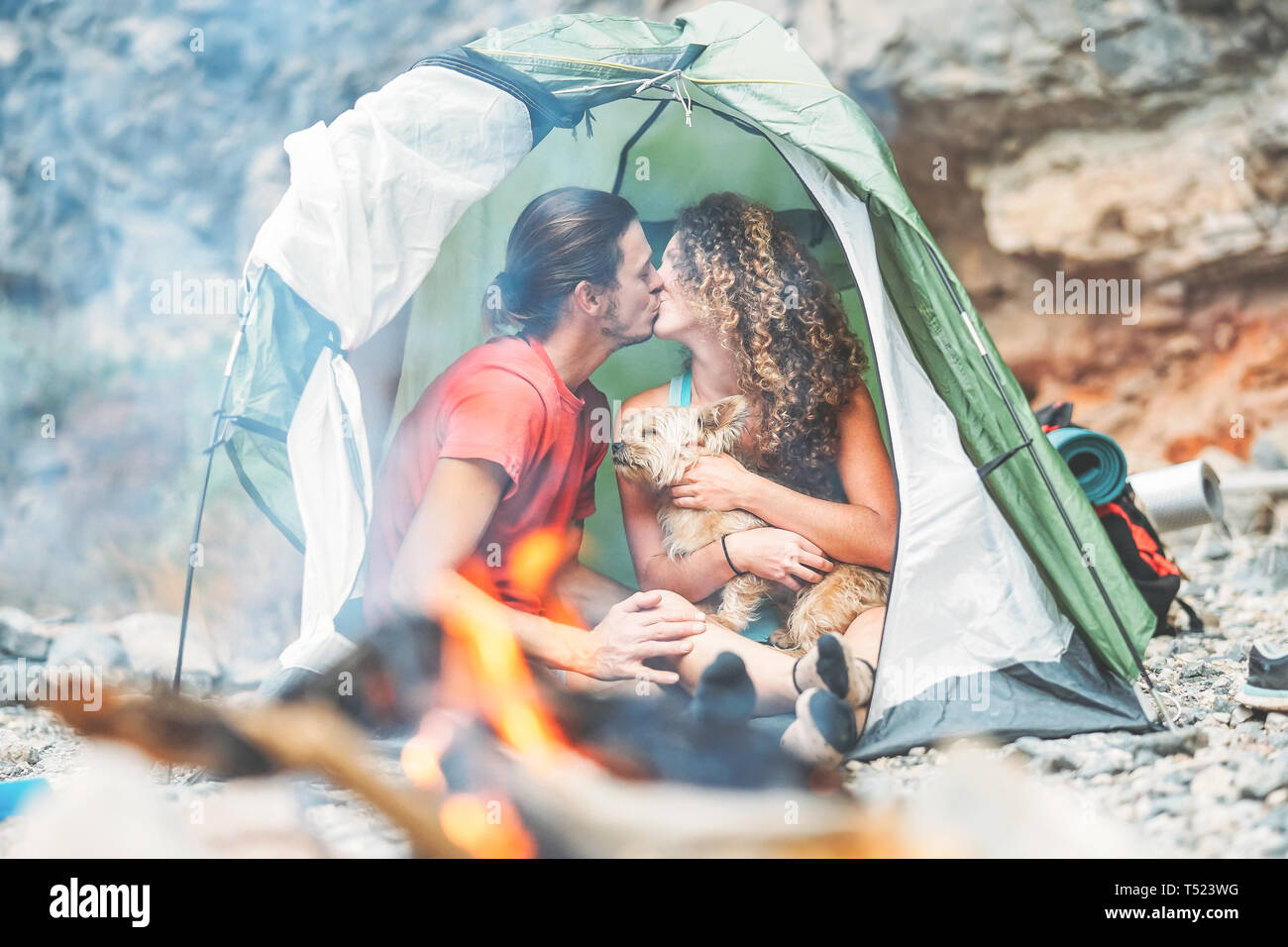 Reisen paar Küssen beim Sitzen im Zelt mit ihrem Haustier - Glücklich der Mann und die Frau in einem romantischen Moment Ferienhäuser Camping rund um Rock Mountain Stockfoto Reisen paar Küssen beim Sitzen im Zelt mit ihrem Haustier - Glücklich der Mann und die Frau in einem romantischen Moment Ferienhäuser Camping rund um Rock Mountain Stockfoto