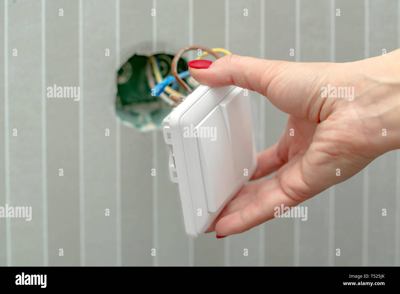 Den Schalter in die weibliche Hand zerlegen. Die Installation des Switch während der Reparatur Stockfoto