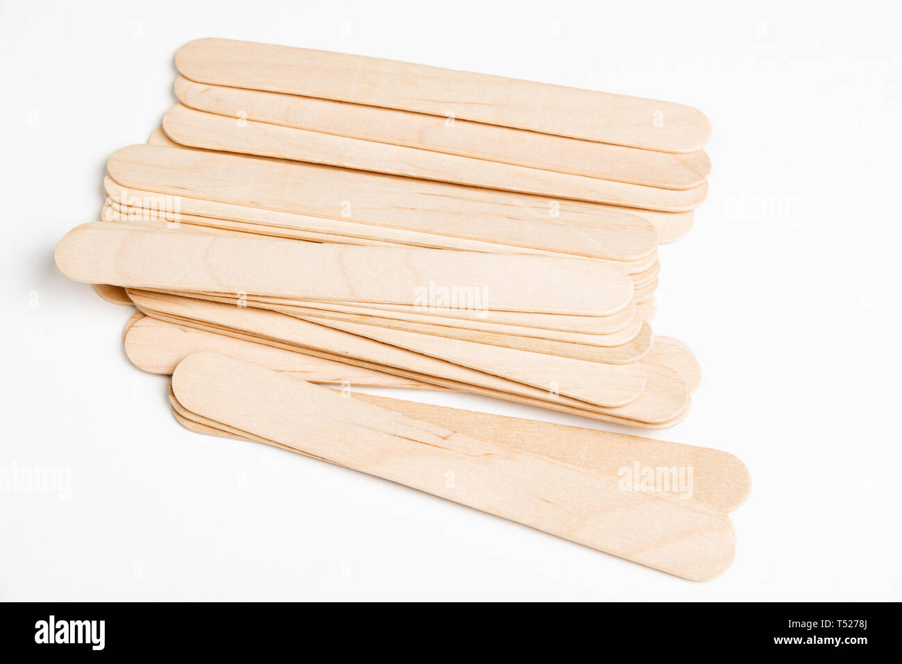 Ein Stapel oder eine Reihe von unbenutzten dicken Holzstäben auf einem schlichten weißen Hintergrund gesetzt. Stockfoto