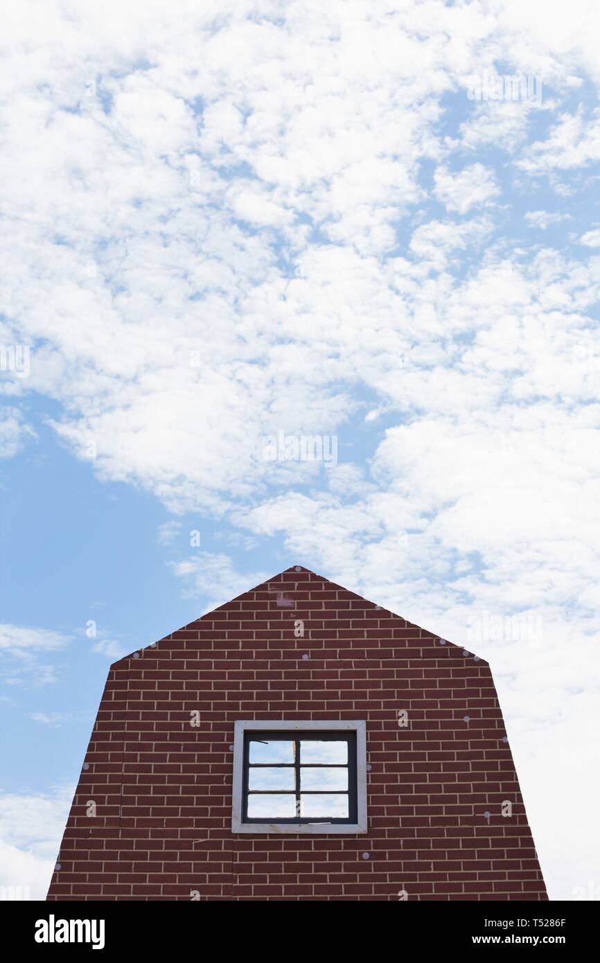 Die Fassade eines Brick House, gegen eine teilweise bewölktem Himmel. Stockfoto