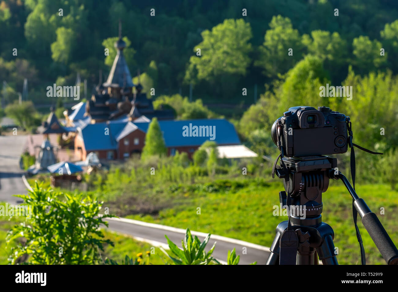 Kamera auf einem Stativ schießt eine hölzerne Kirche in den frühen Morgenstunden Stockfoto