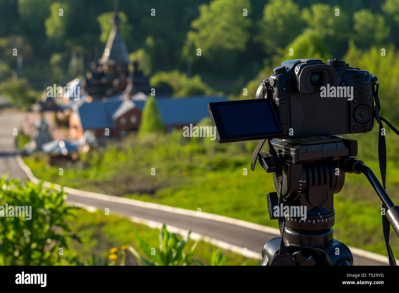 Kamera auf einem Stativ schießt eine hölzerne Kirche in den frühen Morgenstunden Stockfoto