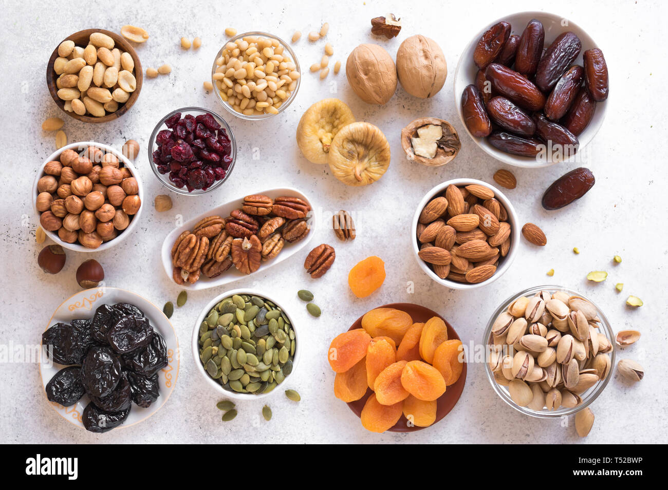 Trockenfrüchte und Nüsse in Schalen auf weißem Hintergrund, Ansicht von oben. Gesunde snack-Sortiment von Bio Trockenfrüchte und Nüsse. Stockfoto