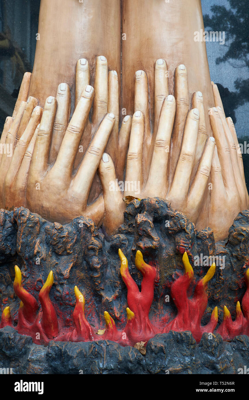 Die Basis eines bemalten Beton Skulptur, die Details der Darstellung Hände bis zu einem Satz von Armen, während unten die Flammen brennen. In Medan, Indonesien. Stockfoto