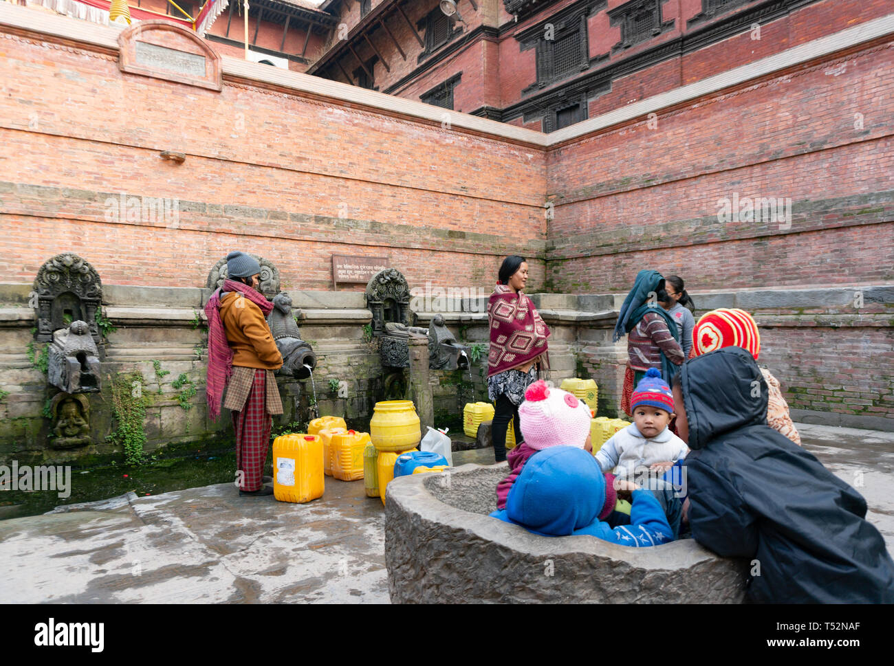 Kathmandu, Nepal - Januar 11, 2016: Lokale Frauen Wasser beim Füllen zu können aus traditionellen Stein Tippen für den täglichen Haushalt Verwendung in Patan. Stockfoto