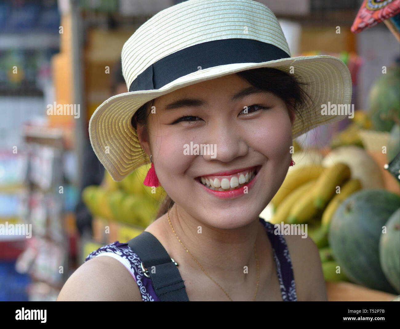 Junge Asiatische Schönheit mit einem Strohhut zeigt eine emotionale Lächeln (natürliche oder spontane [oder "Echte"] Lächeln); Bild.Nr. 2 von 2. Stockfoto