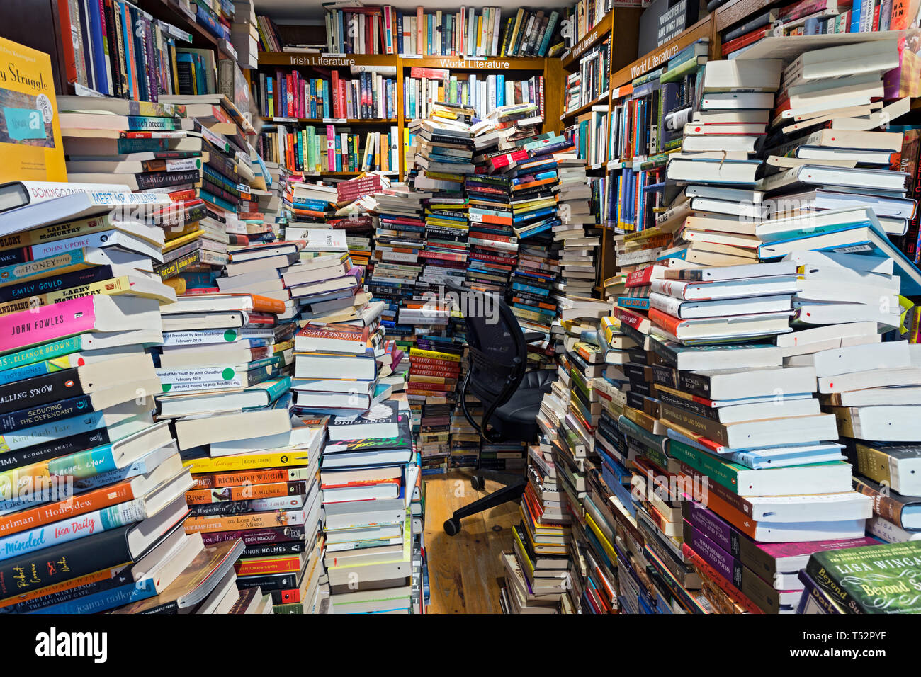 Unordnung und Stapel von Büchern füllen einen Raum für Platz über. Stockfoto