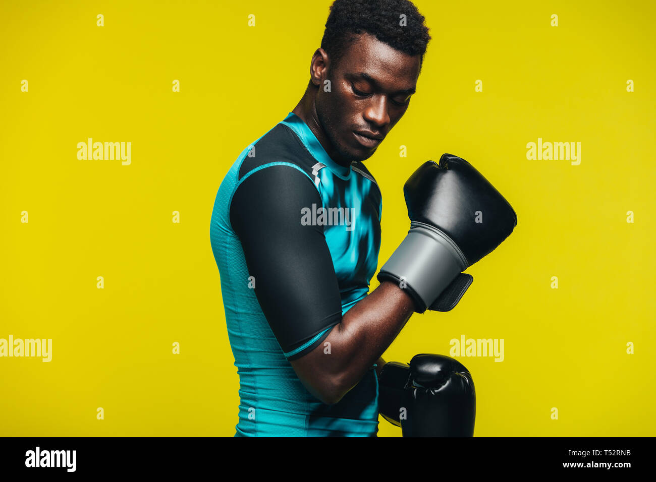 Afrikanischer Mann mit Boxhandschuhen gegen gelben Hintergrund. Passen junge männliche Boxer üben. Stockfoto