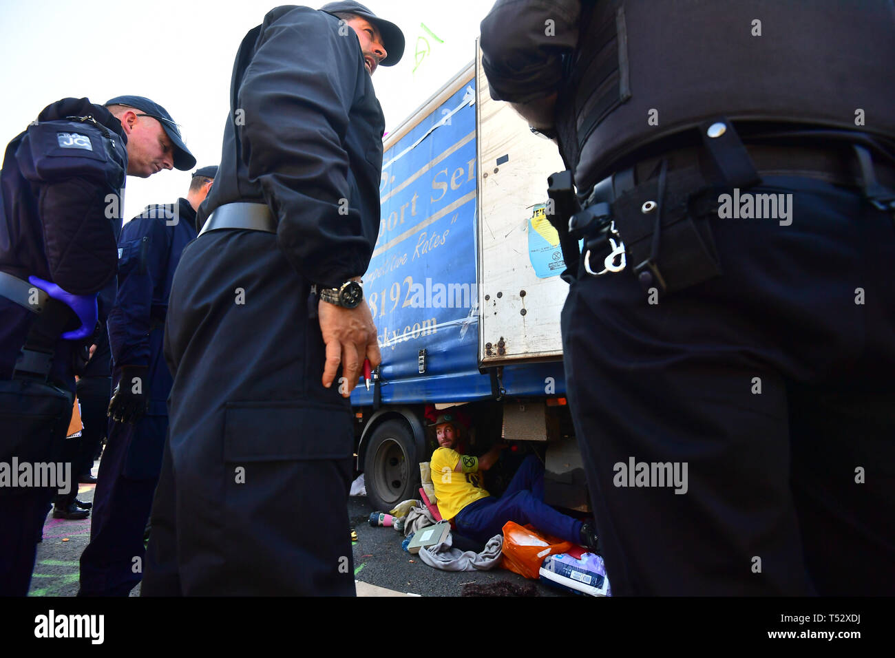 Polizei sprechen zu einem Aussterben Rebellion Demonstrator, der sich an der Unterseite von einem Lkw auf der Waterloo Bridge in London geklebt hat. Stockfoto