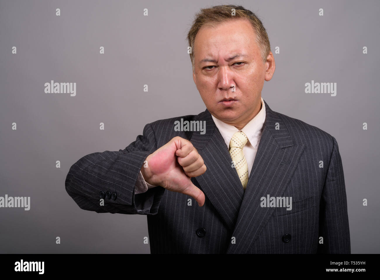 Portrait von Reifen asiatische Geschäftsmann gegen grauer Hintergrund Stockfoto