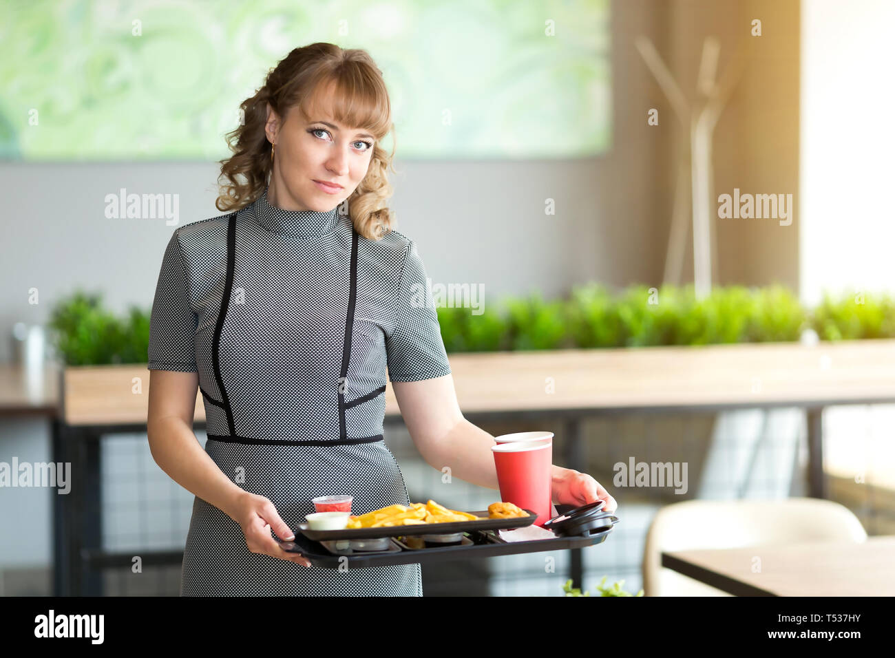 Eine Frau von 30-35 Jahre alt ist, in den Händen ein Dressing auf dem Saft ist Wasser essen Sushi rollen Pommes frites. Stockfoto