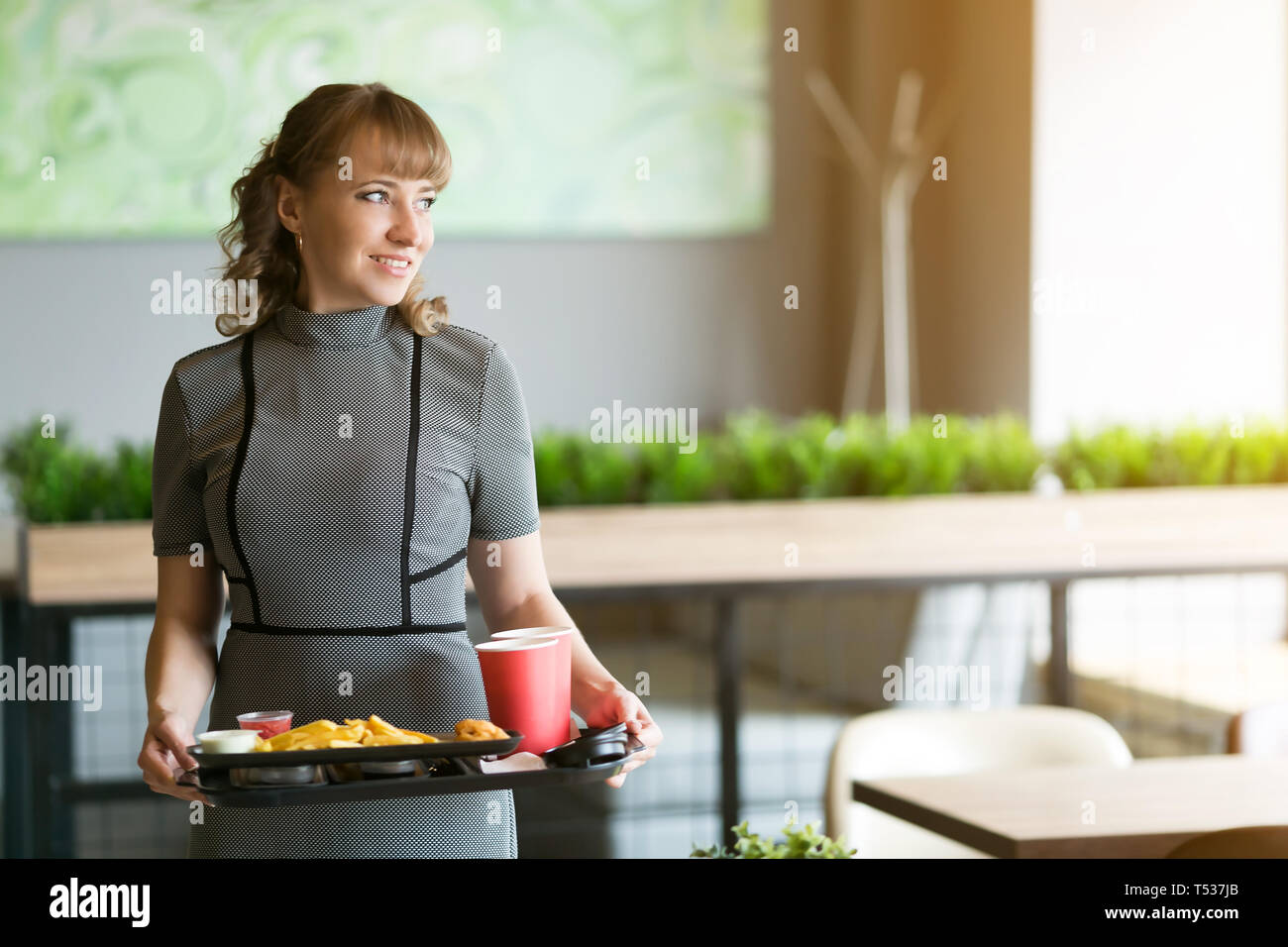 Eine Frau von 30-35 Jahre alt ist, in den Händen ein Dressing auf dem Saft ist Wasser essen Sushi rollen Pommes frites. Stockfoto