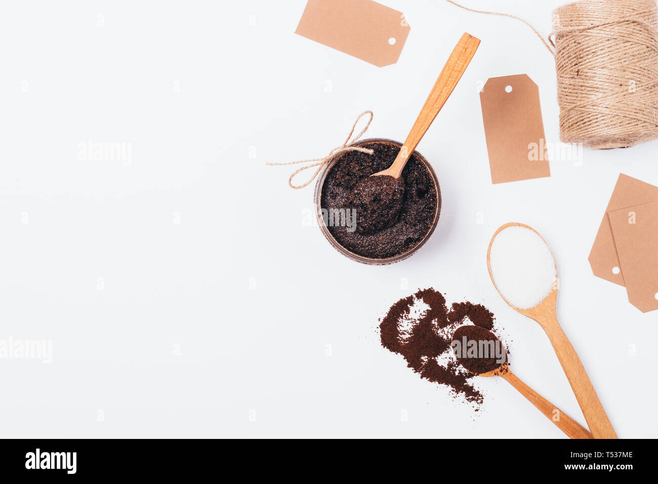 Handgemachte Kosmetik Body Scrub von Kaffee, Zucker und Kokos Öl neben Inhaltsstoffe und Verpackung Etiketten auf weißer Tisch, Kopieren, Ansicht von oben. Stockfoto