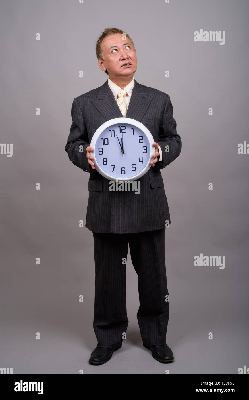 Portrait von Reifen asiatische Geschäftsmann gegen grauer Hintergrund Stockfoto