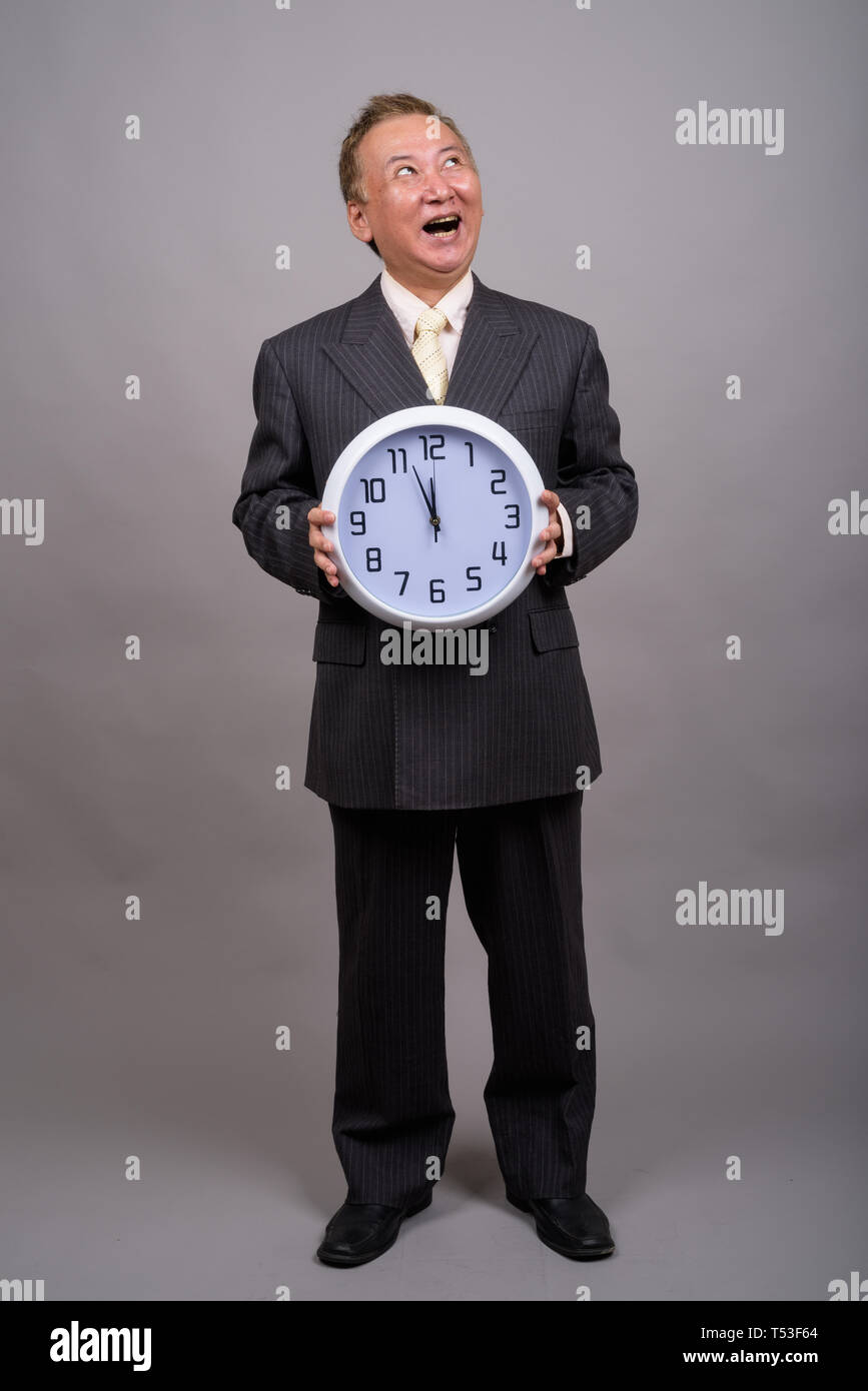 Portrait von Reifen asiatische Geschäftsmann gegen grauer Hintergrund Stockfoto