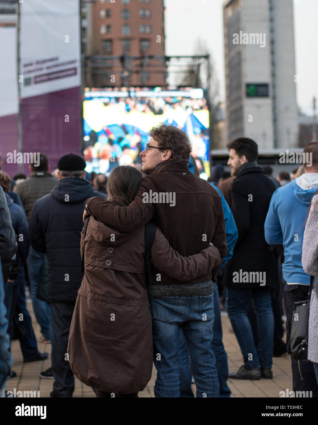 Ein paar Umarmungen zusammen auf dem Platz in der Nähe von Kiew Olympiyskiy Stadion am Präsidentendebatte Ereignis. Menge und Polizeikorps in Aktion. Stockfoto