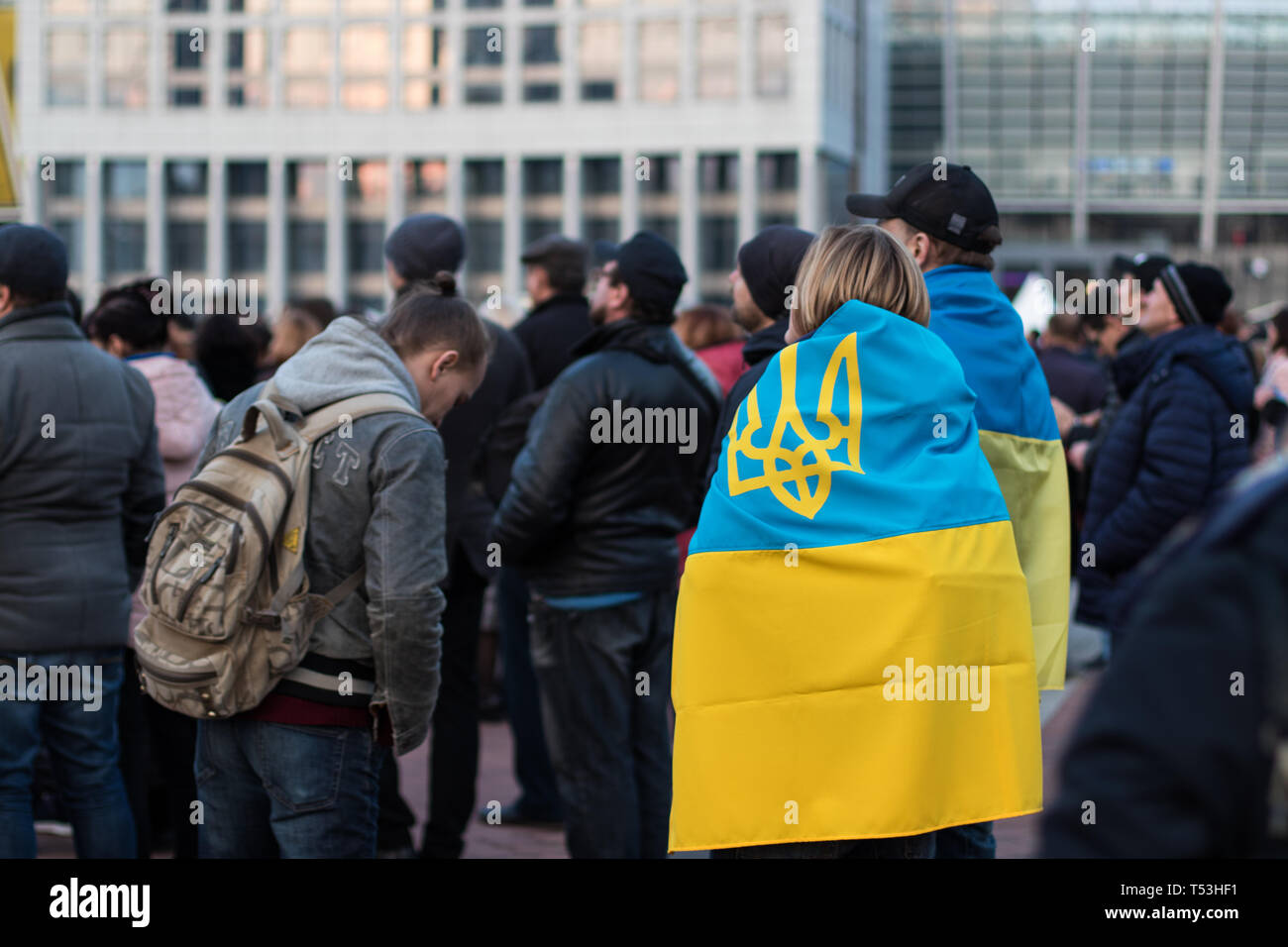 Ein paar mit ukrainischen Banner auf ihrem Rücken in der Nähe von Kiew Olympiyskiy Stadion am Präsidentendebatte Ereignis. Menge und Polizeikorps in Aktion. Stockfoto