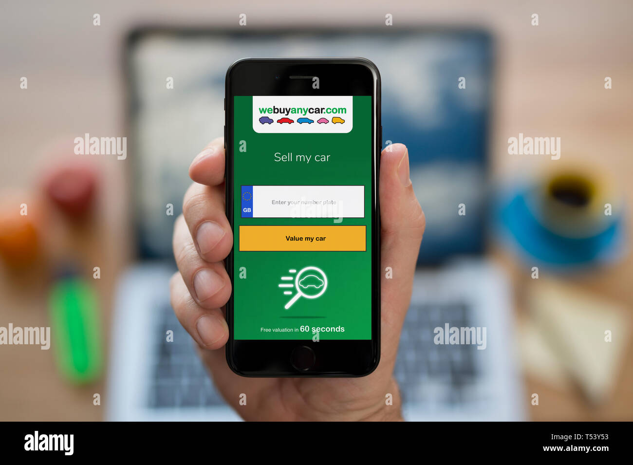 Ein Mann schaut auf seinem iPhone die zeigt die Wir jedes Auto logo Kaufen (nur redaktionelle Nutzung). Stockfoto