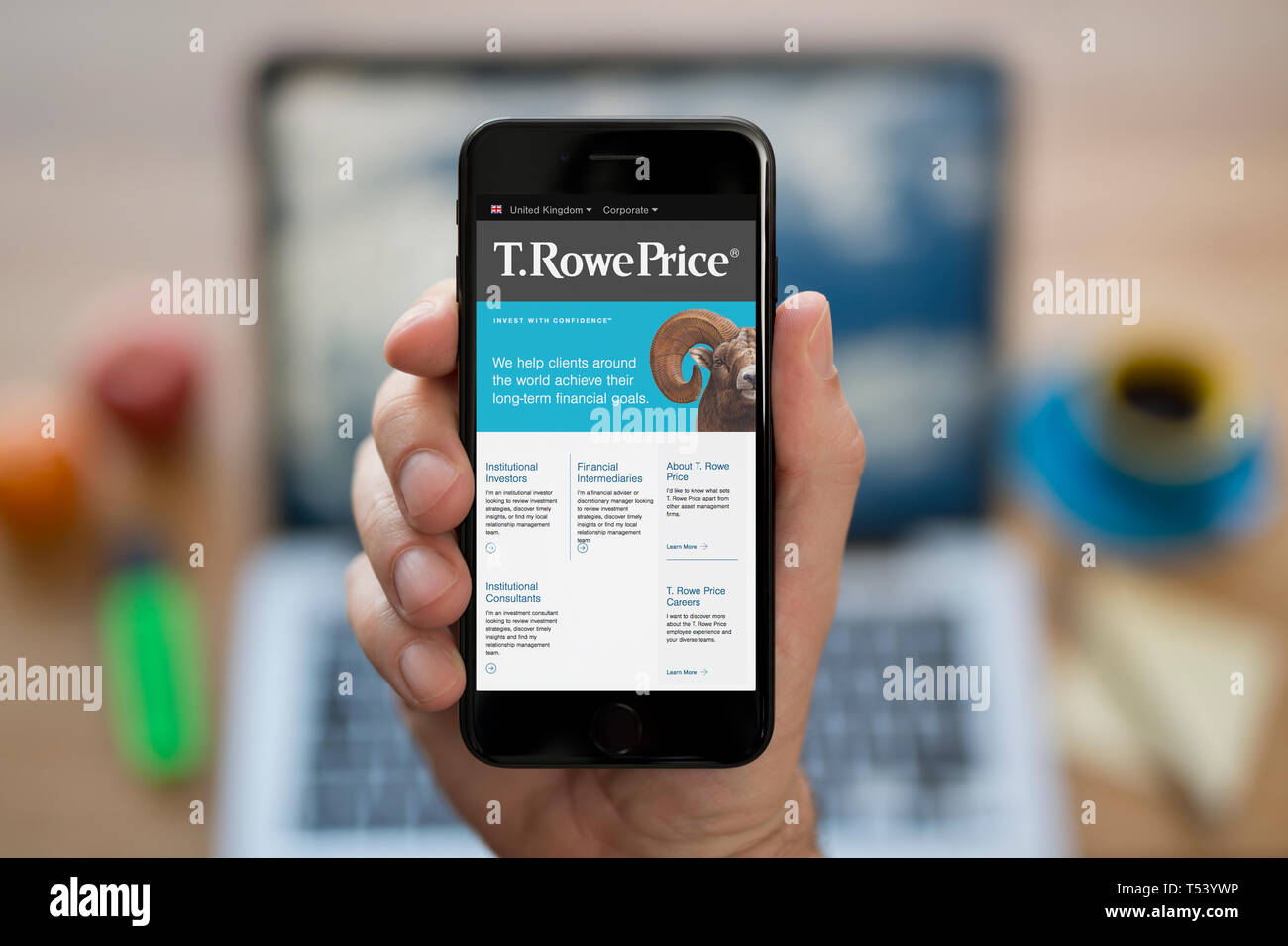 Ein Mann schaut auf seinem iPhone die zeigt die T.Rowe Preis Logo (nur redaktionelle Nutzung). Stockfoto