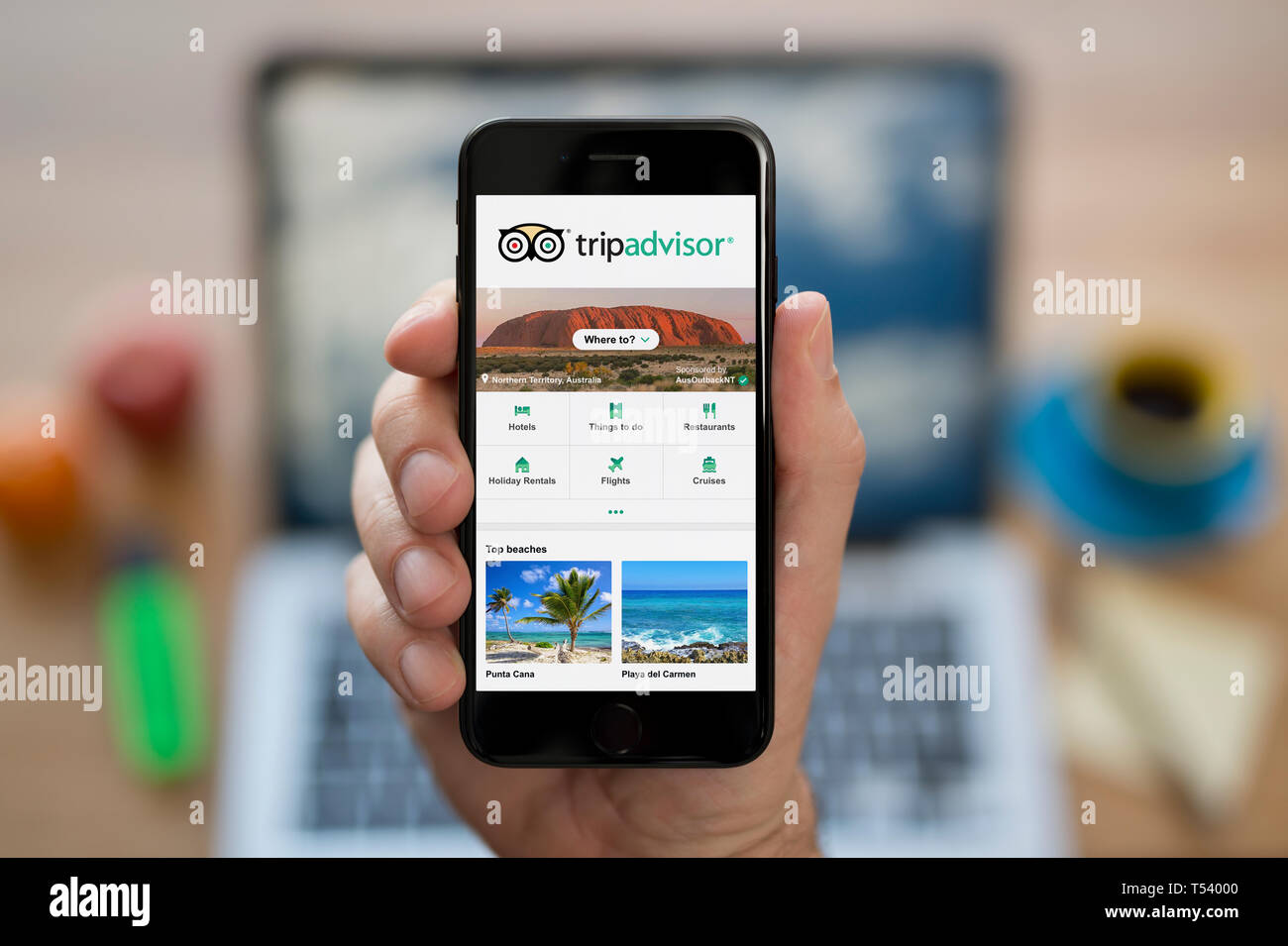 Ein Mann schaut auf seinem iPhone wird der Trip Advisor Logo (nur redaktionelle Nutzung). Stockfoto