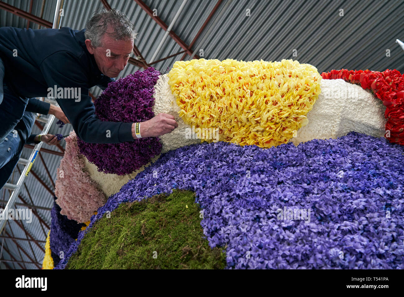 Teilnehmer mit Blumen die Schwimmer, die sich in der Parade der Blume Anbaugebiet in Holland teilnehmen wird. Stockfoto