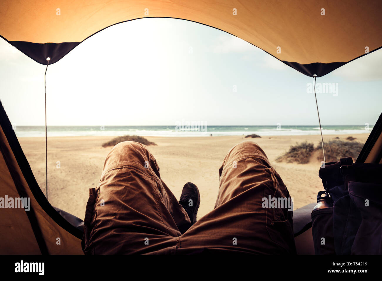 Alternative Ferienhäuser Konzept mit Mann in trekking Kleidung außerhalb des Zeltes campiing kostenlos am Strand Blick auf das Meer Horizont und genießen. zur Festlegung Stockfoto Alternative Ferienhäuser Konzept mit Mann in trekking Kleidung außerhalb des Zeltes campiing kostenlos am Strand Blick auf das Meer Horizont und genießen. zur Festlegung Stockfoto