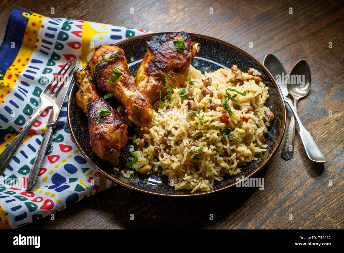 Afrikanische Küche gegrillte Hähnchenkeulen mit jollof Reis mit orzo und Black Eyed Peas Stockfoto