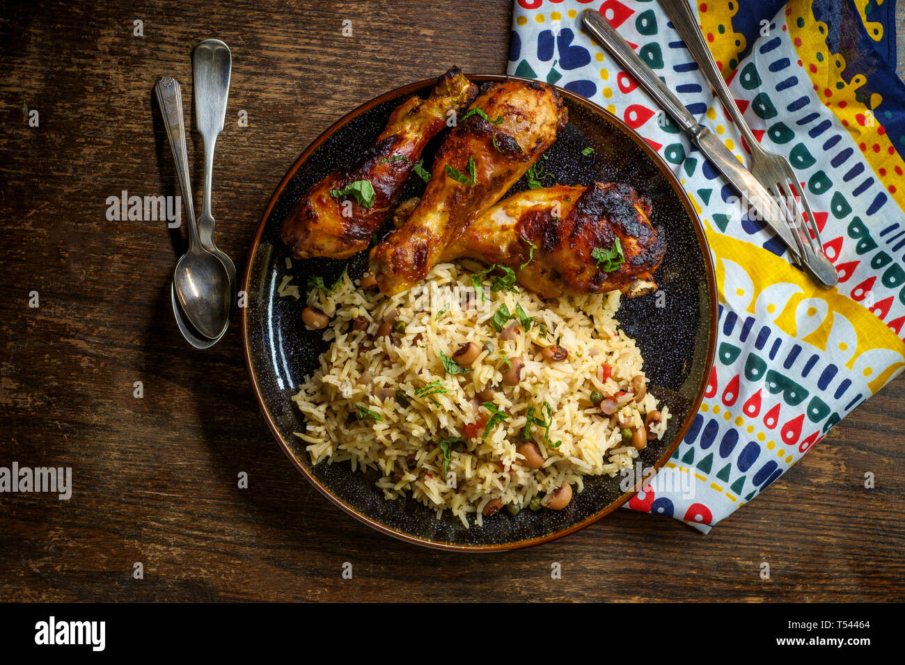 Afrikanische Küche gegrillte Hähnchenkeulen mit jollof Reis mit orzo und Black Eyed Peas Stockfoto
