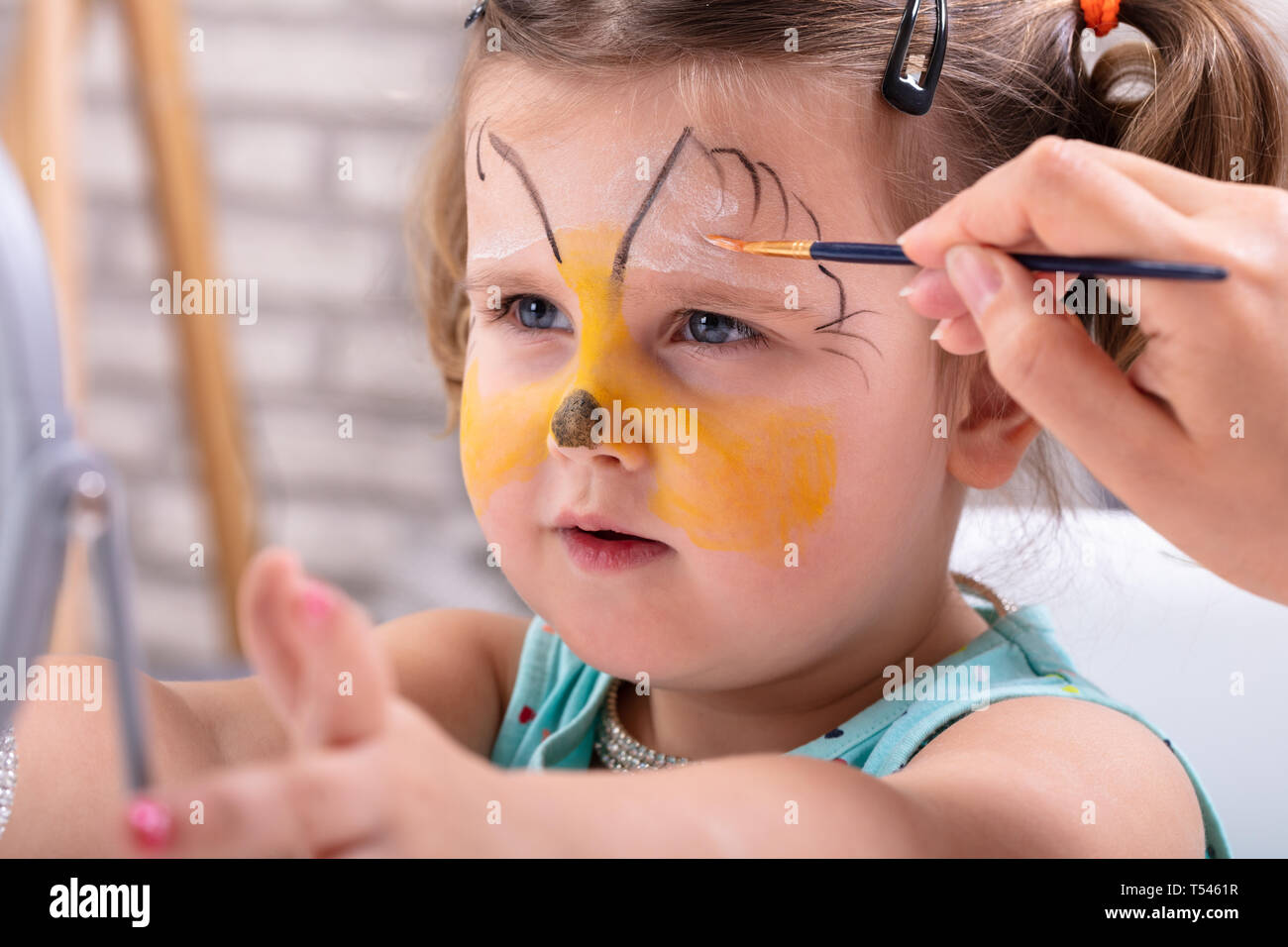 Malerei das Gesicht eines kleinen Mädchen mit Farbe, Pinsel Stockfoto