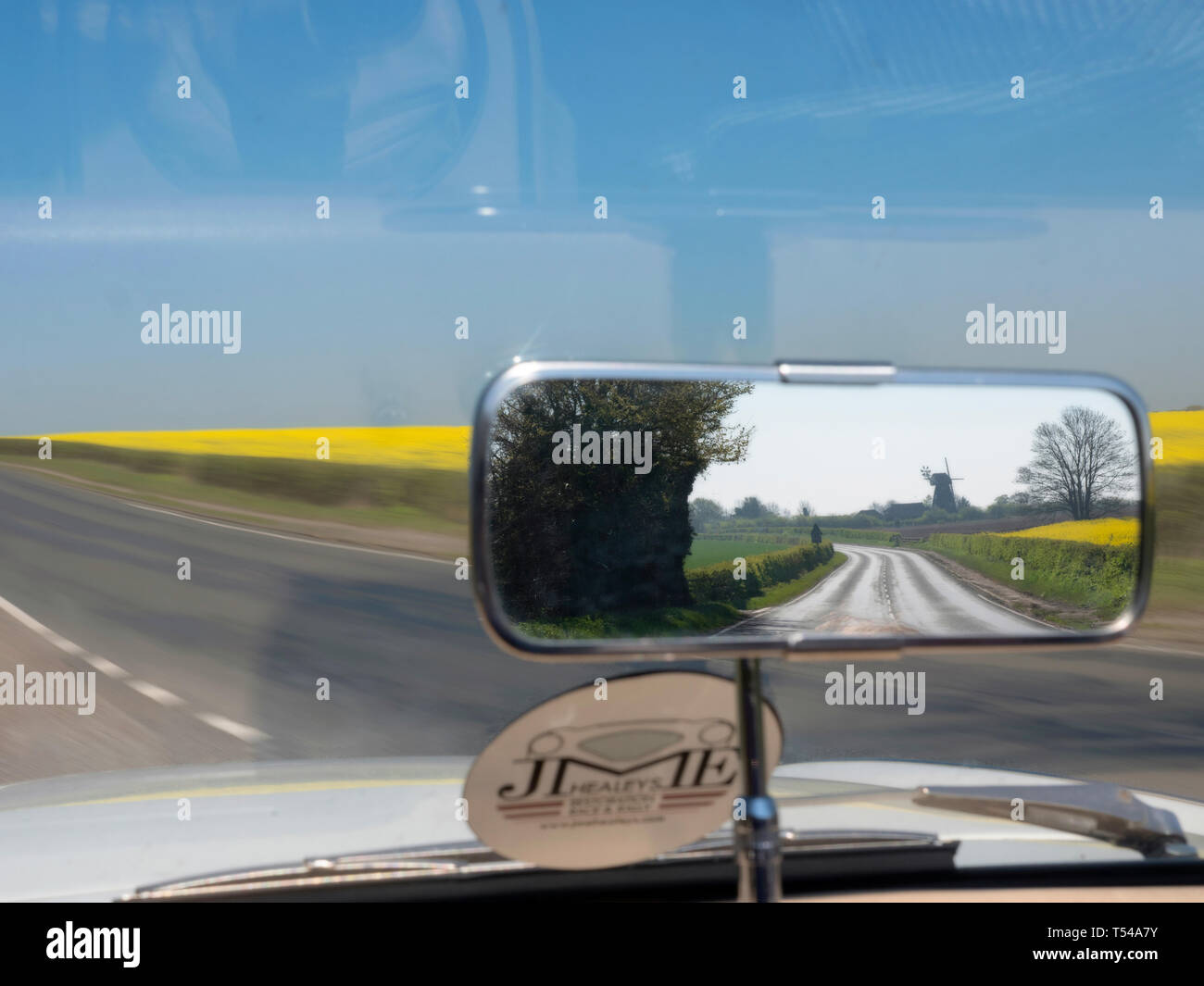 Classic Car Fahrer Blick in den Rückspiegel beim Fahren auf einer Straße in Kent, Großbritannien Stockfoto