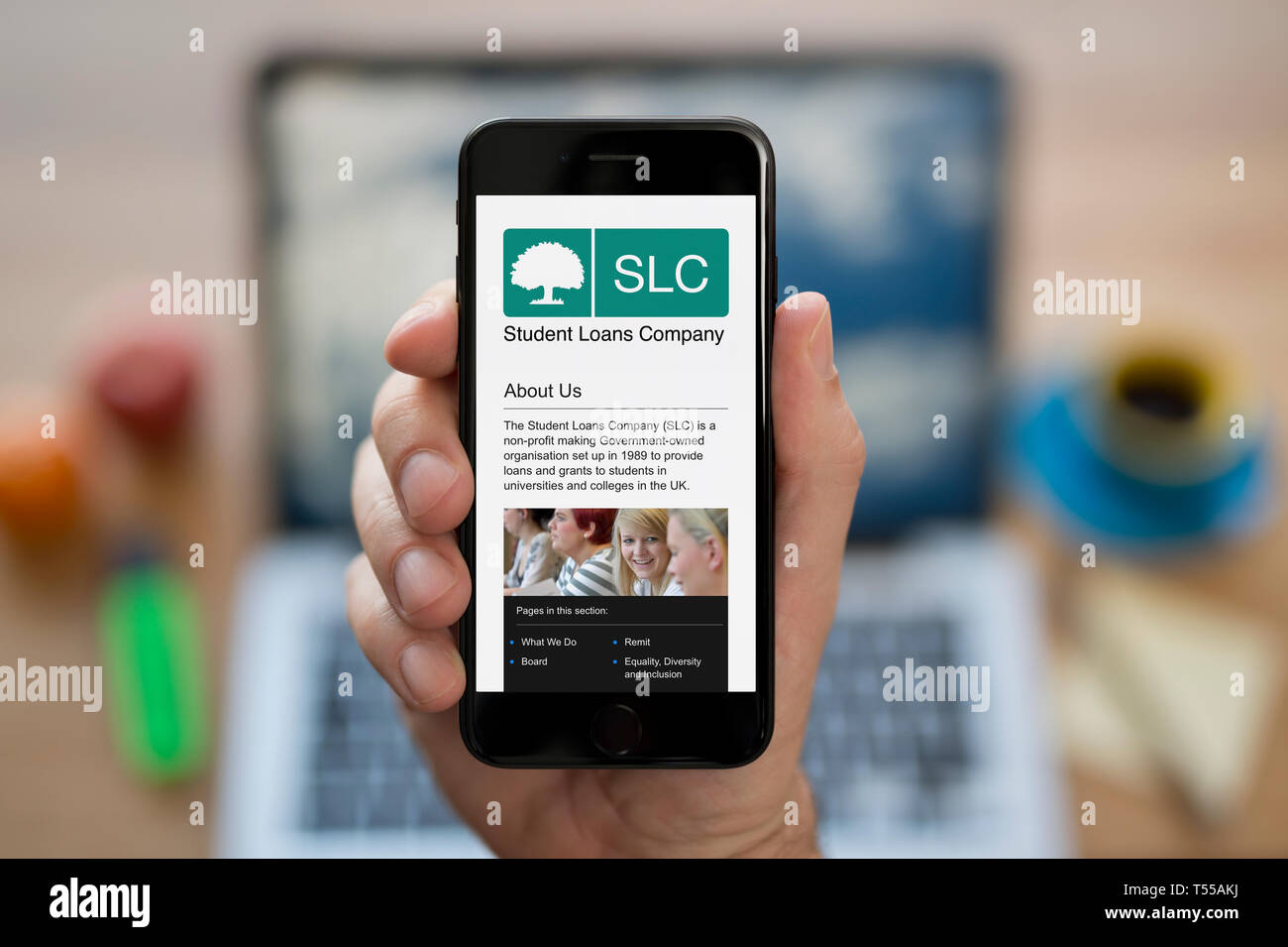 Ein Mann schaut auf seinem iPhone wird der Student Loans Company Logo (nur redaktionelle Nutzung). Stockfoto