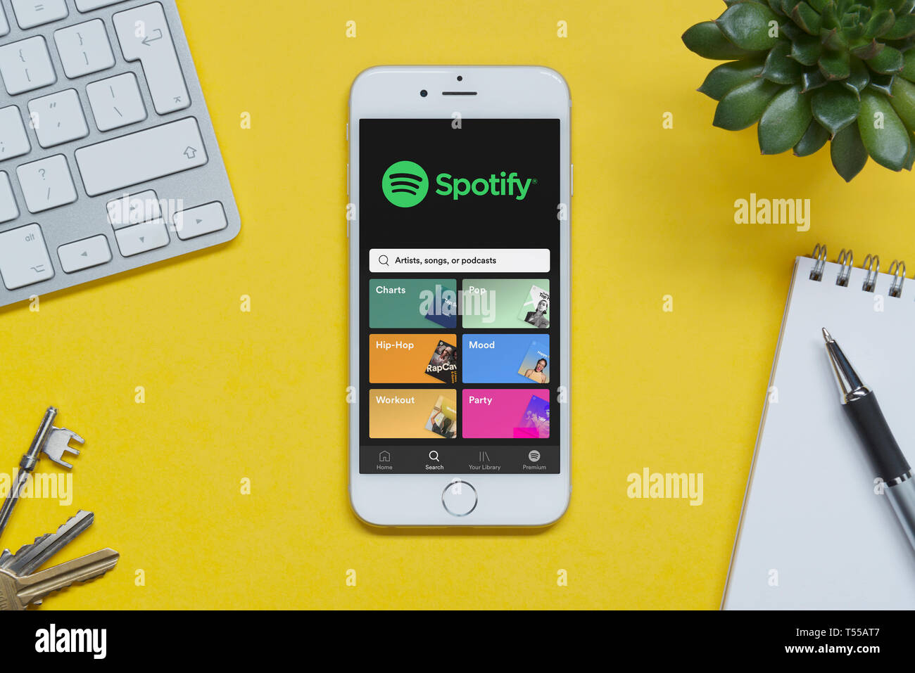 Ein iPhone mit Spotify website ruht auf einem gelben Hintergrund Tabelle mit einer Tastatur, Tasten, Notepad und Anlage (nur redaktionelle Nutzung). Stockfoto