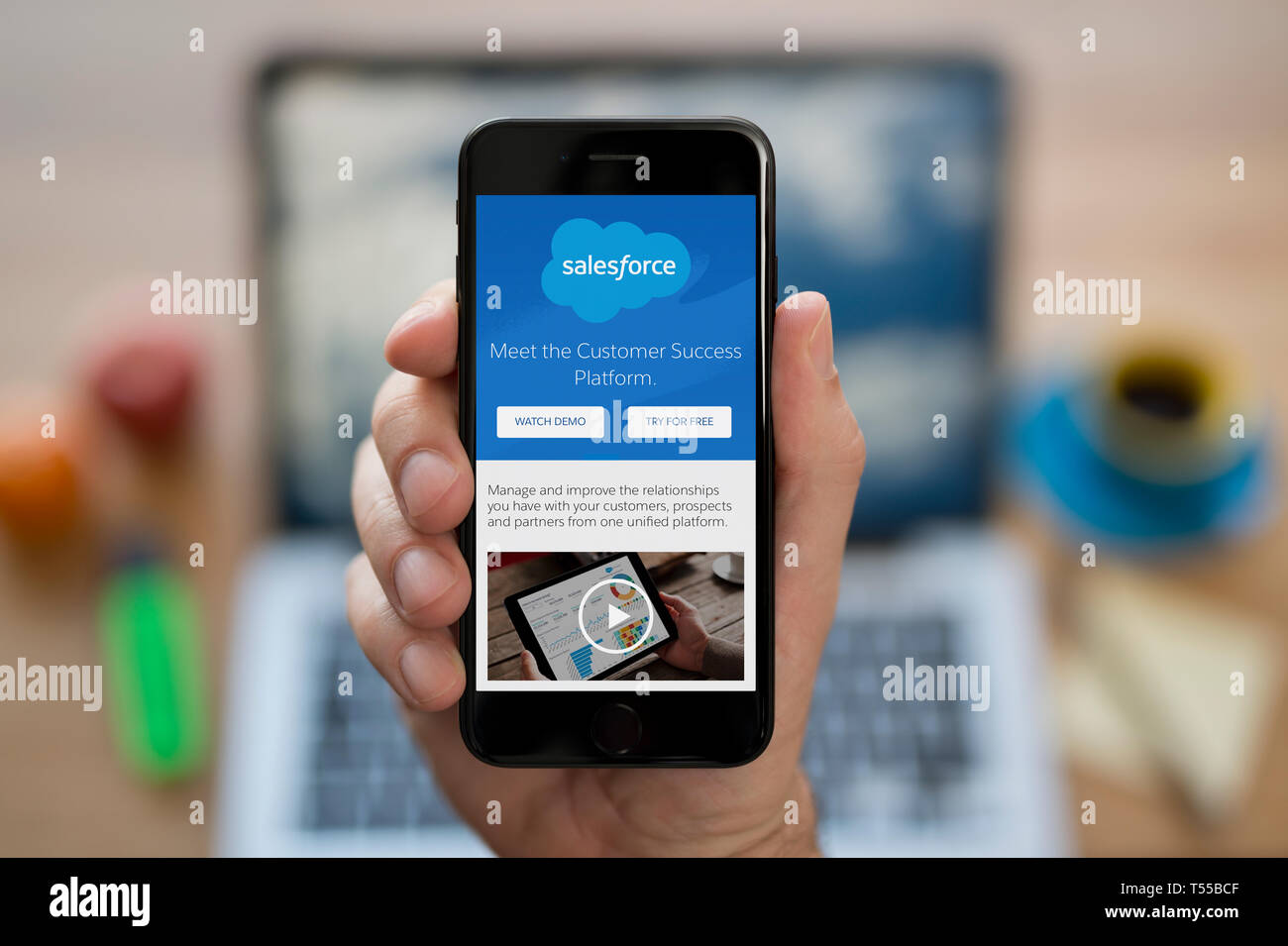 Ein Mann schaut auf seinem iPhone die zeigt die Salesforce Logo (nur redaktionelle Nutzung). Stockfoto