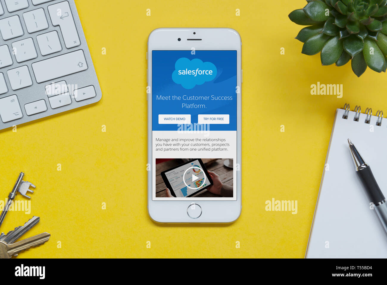 Ein iPhone mit der Salesforce-website ruht auf einem gelben Hintergrund Tabelle mit einer Tastatur, Tasten, Notepad und Anlage (nur redaktionelle Nutzung). Stockfoto