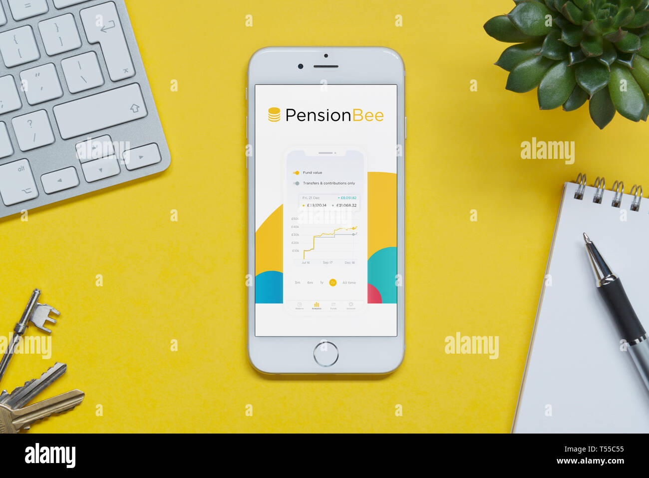 Ein iPhone zeigt die Pension Bee website ruht auf einem gelben Hintergrund Tabelle mit einer Tastatur, Tasten, Notepad und Anlage (nur redaktionelle Nutzung). Stockfoto Ein iPhone zeigt die Pension Bee website ruht auf einem gelben Hintergrund Tabelle mit einer Tastatur, Tasten, Notepad und Anlage (nur redaktionelle Nutzung). Stockfoto