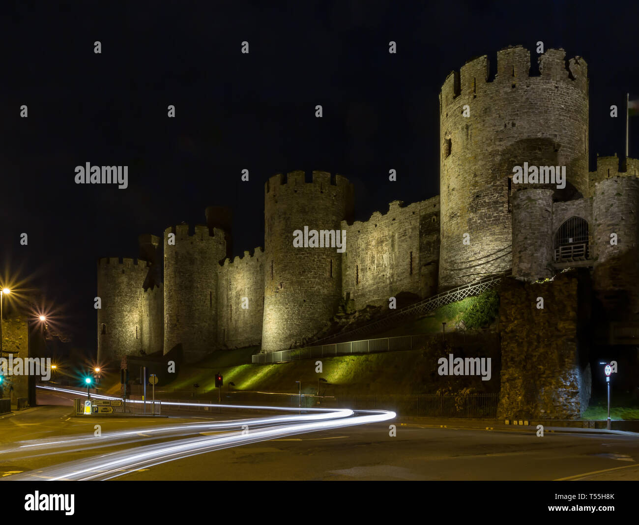 Conway Castle in Wales, in der Nacht mit Licht von vorbeifahrenden Autos Erstellen von Pfaden Stockfoto