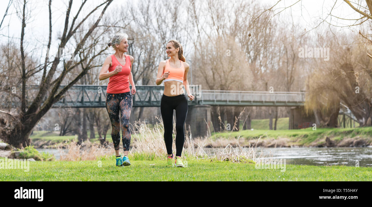 Ältere und junge Frau läuft als Sport auf einer Wiese im Frühjahr Stockfoto