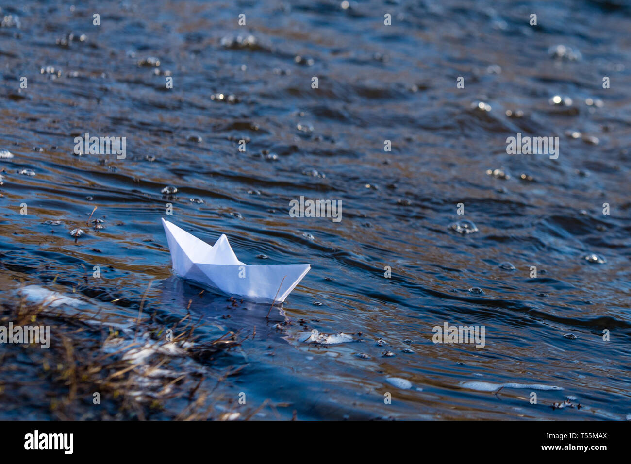 Ein Papier Boot auf eine turbulente Strom von Wasser kämpft mit der Strömung. Kleines Papier Boot fließt entlang des Flusses Stockfoto